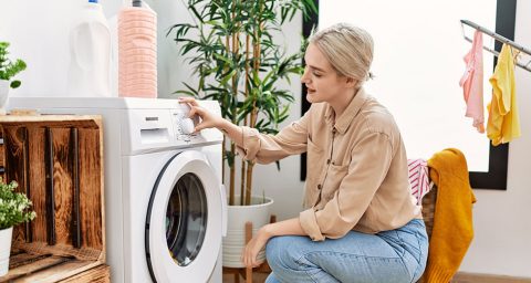 Vrouw stelt wasprogramma in op een wasmachine in een moderne wasruimte
